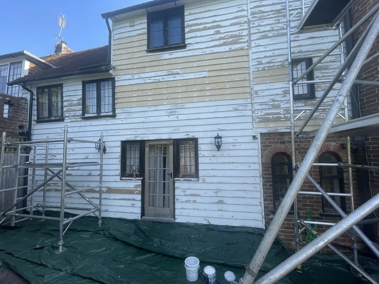 Weatherboard repair and board replacement in progress on the rear elevation of a Grade II listed oast house near Rye, with sound original boards retained